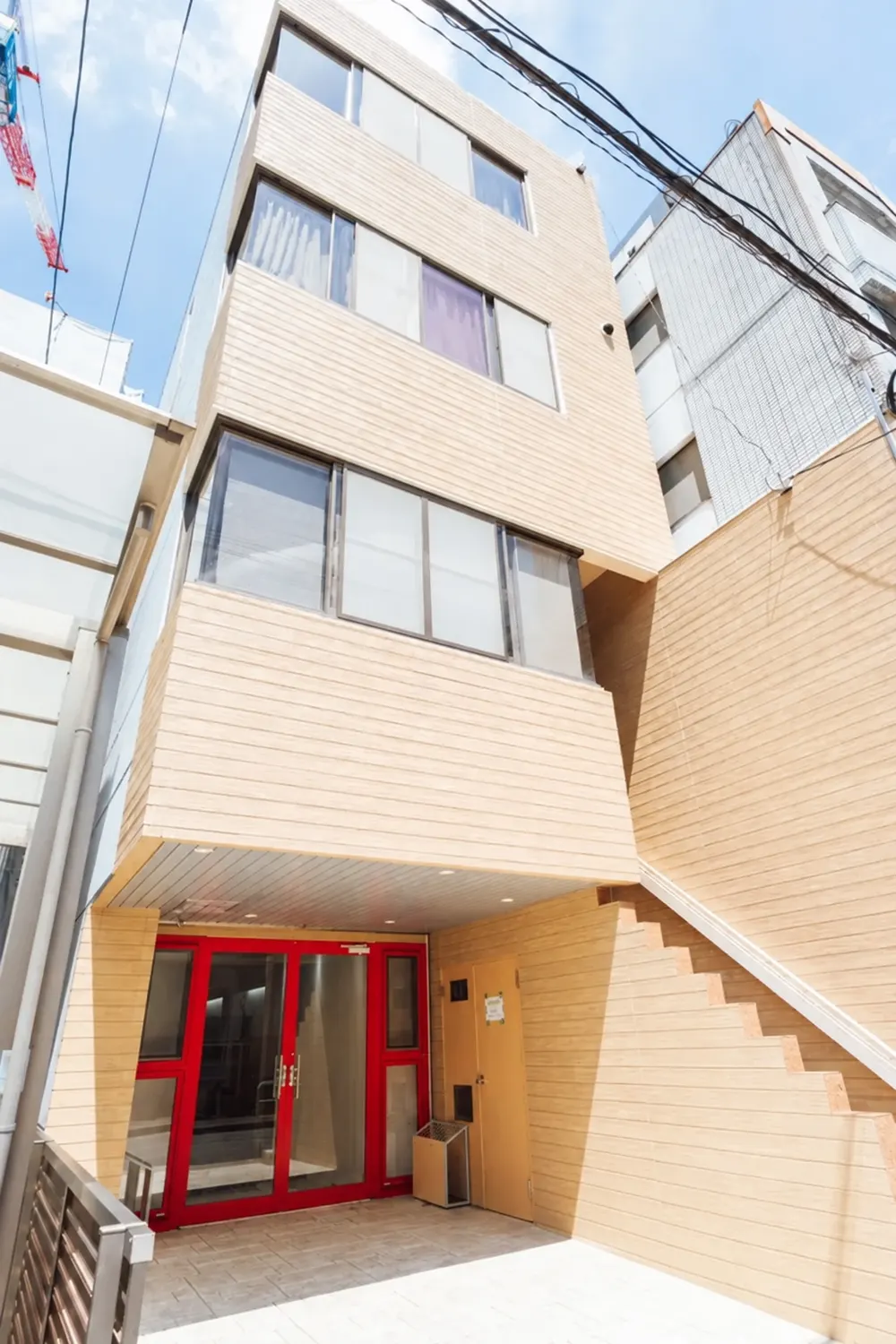 Base Placeの外観。木目調の4階建てビルと赤い枠の入口。